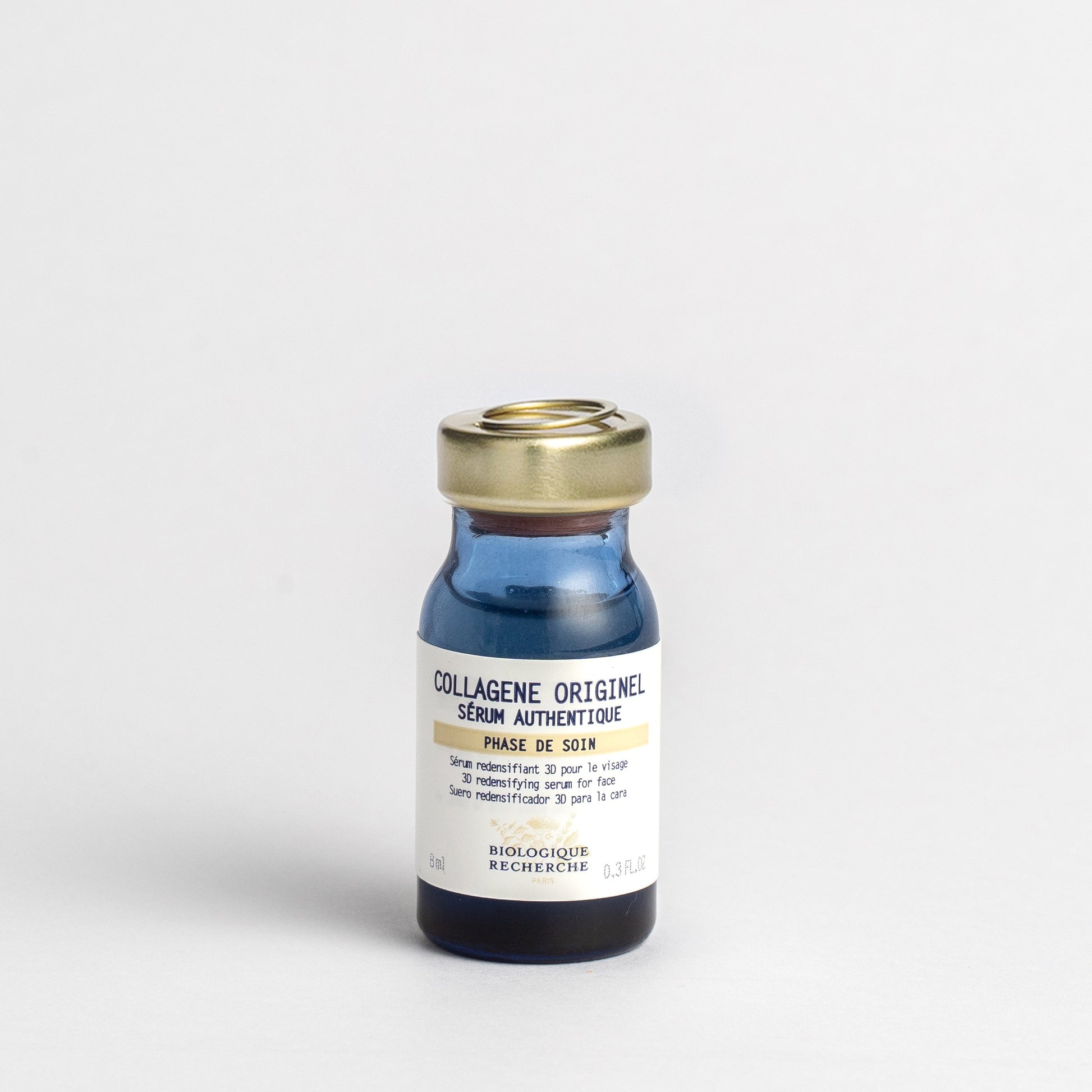 Bottle of 'Collagène Originel' serum with a gold cap on a light gray background 8ml